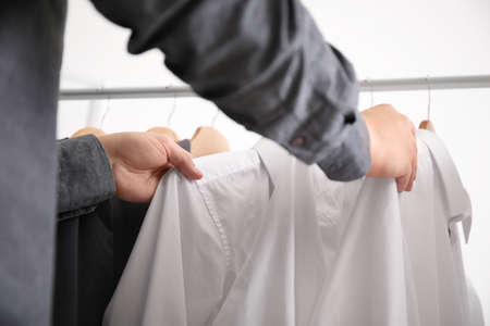 Young male stylist choosing clothes from rack, closeupの写真素材