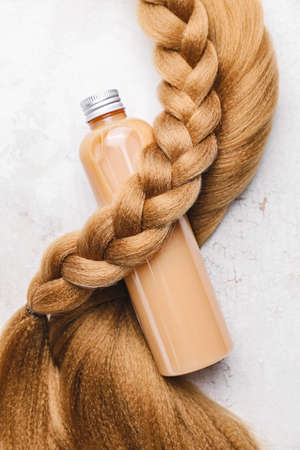 Bottle of shampoo and hair strand on white backgroundの写真素材