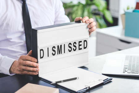 Man holding board with text DISMISSED in officeの写真素材