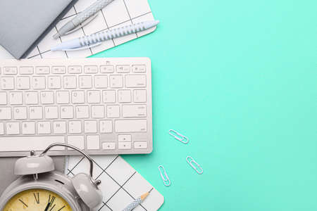 School supplies with alarm clock and computer keyboard on color backgroundの写真素材