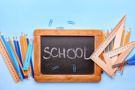 Set of supplies and chalkboard with text SCHOOL on color backgroundの写真素材