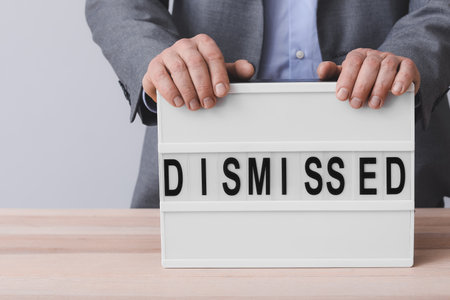 Man and board with text DISMISSED on tableの写真素材