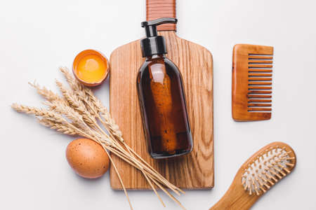 Shampoo with natural extract, comb and brush on white backgroundの写真素材