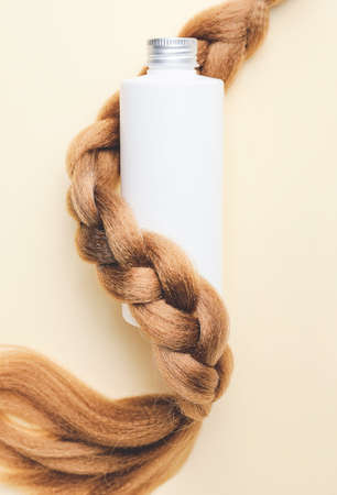 Bottle of shampoo and hair strand on color backgroundの写真素材