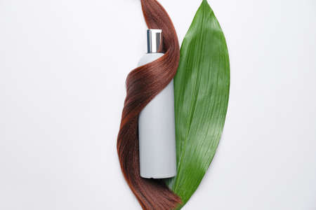 Bottle of shampoo, leaf and hair strand on white backgroundの写真素材