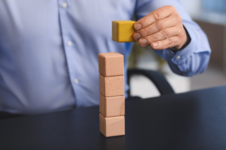 Man removing cube from stack on table. Concept of dismissalの写真素材