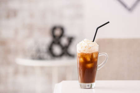 Glass cup of tasty iced coffee on table in cafe