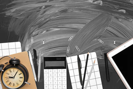 School supplies with alarm clock and tablet computer on dark backgroundの写真素材