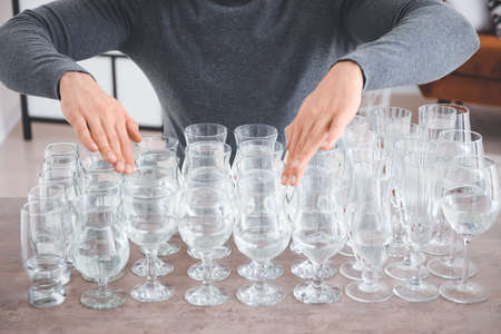 Young man playing music on glasses with water at homeの写真素材