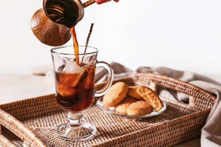Pouring of coffee into in glass cup with ice cubes on trayの写真素材