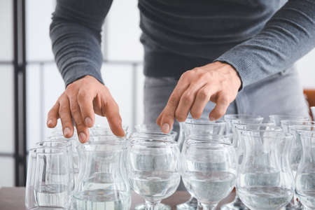 Young man playing music on glasses with water at home, closeupの写真素材