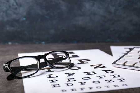 Eye test chart with eyeglasses on dark backgroundの写真素材