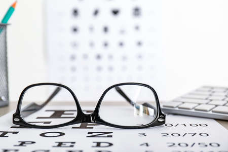 Eye test chart with eyeglasses on table, closeupの写真素材