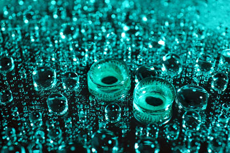 Contact lenses on dark color background with water drops