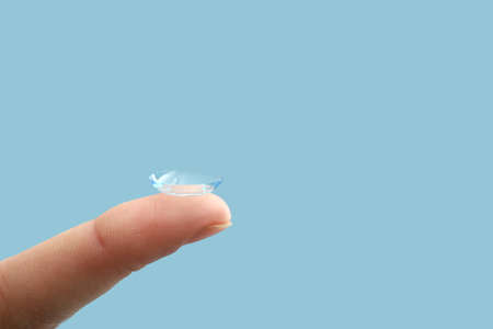 Female finger with contact lens on color backgroundの写真素材