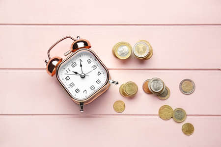 Alarm clock and coins on wooden table. Time management conceptの写真素材