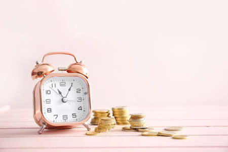 Alarm clock and coins on wooden table. Time management concept