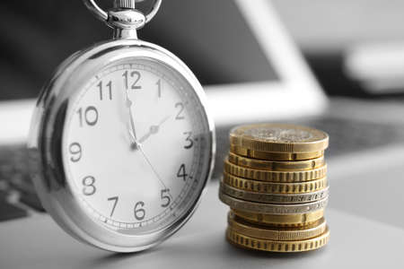 Coins and clock on laptop, closeup. Time management conceptの写真素材