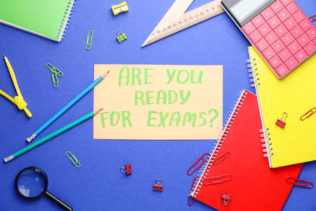 Stationery and paper sheet with text ARE YOU READY FOR EXAMS? on color backgroundの写真素材