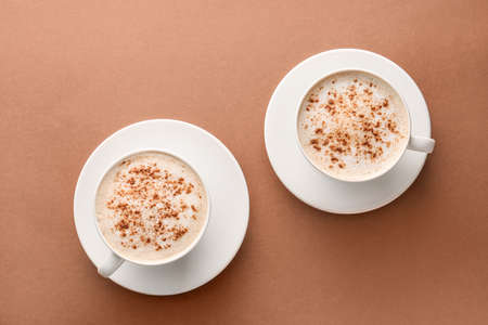 Cups of tasty cappuccino on color backgroundの写真素材