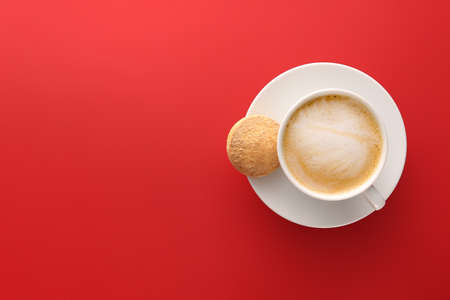 Cup of tasty cappuccino and cookie on color backgroundの写真素材