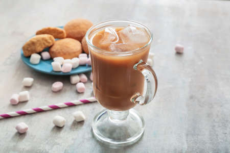 Glass cup of tasty iced coffee with sweets on gray backgroundの写真素材
