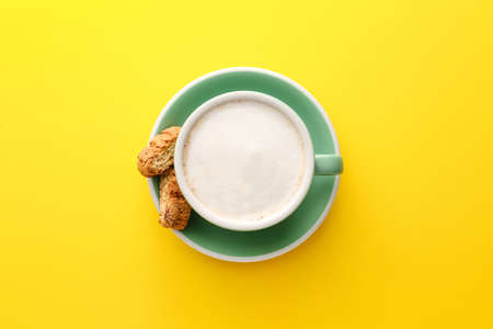 Cup of tasty cappuccino and cookies on color backgroundの写真素材