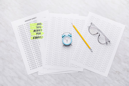 Answer sheet forms with alarm clock on white background. Concept of preparation for examの写真素材
