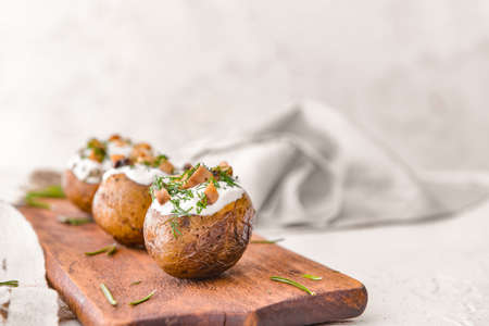 Tasty baked potato with sour cream and mushrooms on boardの写真素材