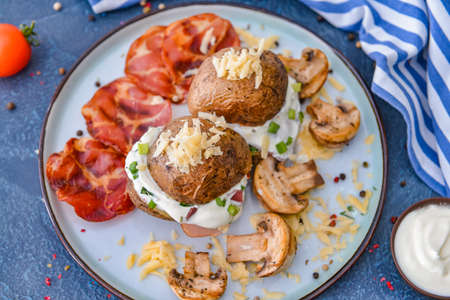 Tasty baked potato with sour cream, bacon and mushrooms on plateの写真素材