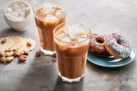 Glasses of tasty iced coffee with sweets on gray backgroundの写真素材