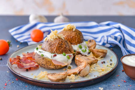 Tasty baked potato with sour cream, bacon and mushrooms on plateの写真素材