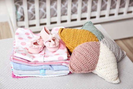 Baby clothes with booties and pillow on table in room