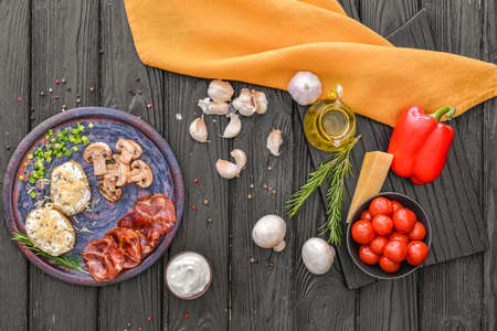 Tasty baked potato with sour cream, mushrooms and bacon on tableの写真素材