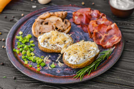 Tasty baked potato with sour cream, mushrooms and bacon on tableの写真素材