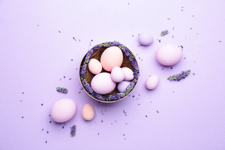 Box with beautiful Easter eggs and flowers on color backgroundの写真素材