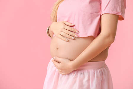 Beautiful young pregnant woman on color backgroundの写真素材