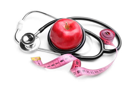 Fresh apple, measuring tape and stethoscope on white backgroundの写真素材