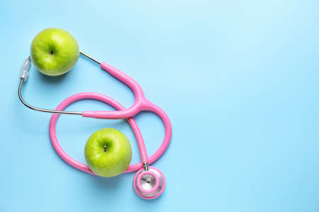 Fresh apples and stethoscope on color backgroundの写真素材