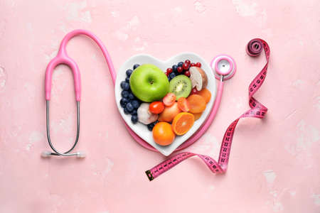 Plate with healthy products, stethoscope and measuring tape on color backgroundの写真素材