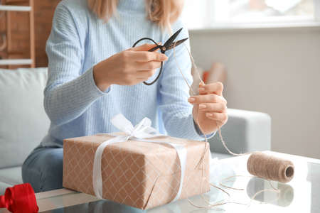 Beautiful young woman wrapping Christmas gifts at home