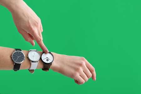 Female hands with wrist clocks on color background. Time management concept