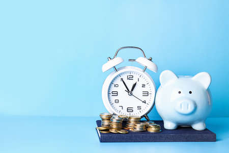 Alarm clock, piggy bank and coins on color background. Time management conceptの写真素材