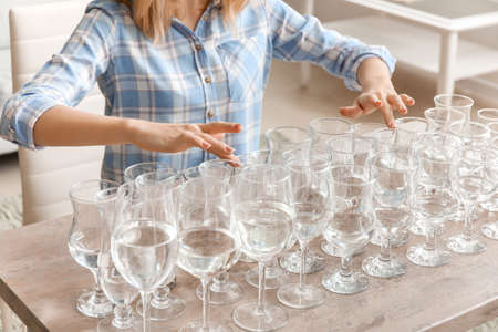 Young woman playing music on glasses with water at homeの写真素材