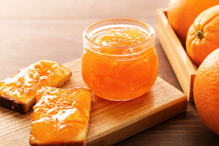 Jar of orange jam with slices of bread on tableの写真素材