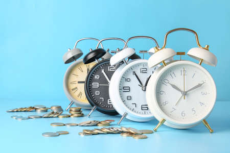 Alarm clocks and coins on color background. Time management concept