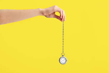 Female hand with pocket clock on color background. Time management conceptの写真素材