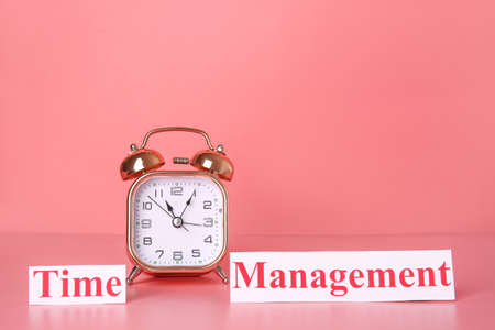 Alarm clock and text TIME MANAGEMENT on color backgroundの写真素材