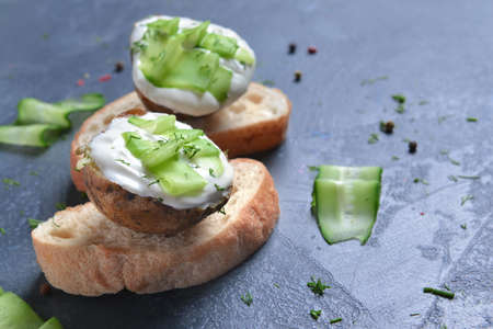Tasty baked potato with sour cream, cucumber and bread on dark backgroundの写真素材