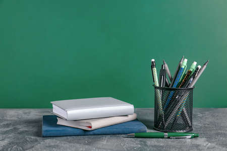 Holder with stationery on table near blackboardの写真素材